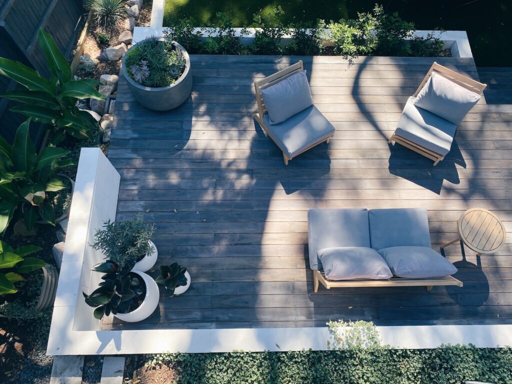 Aerial view of a wooden patio with cushioned seating and surrounded by greenery and potted plants exterior designed in Ibiza